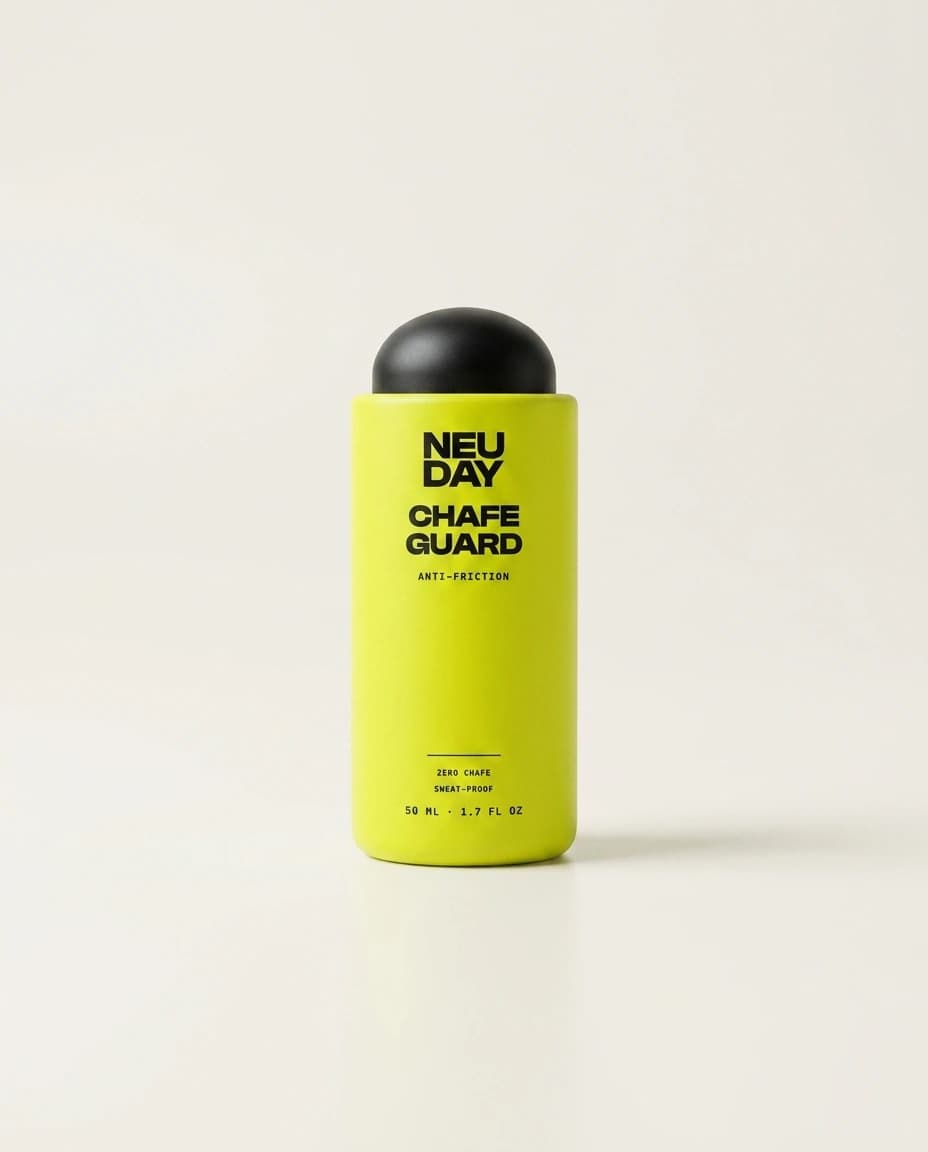 NEUDAY Chafe Guard anti-friction roll-on — a volt-yellow 50ml roll-on bottle with a matte-black collar, on a warm bone studio background